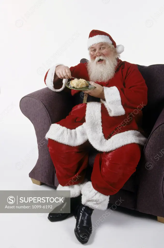 Portrait of Santa Claus sitting in an armchair eating a pie