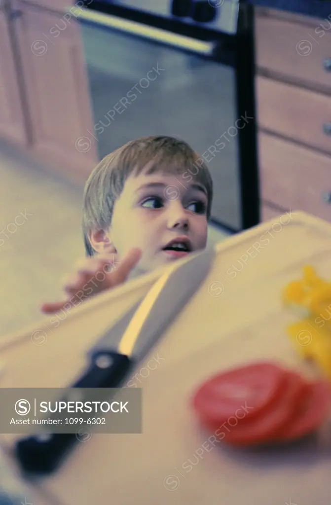 Boy reaching for a knife on a kitchen counter