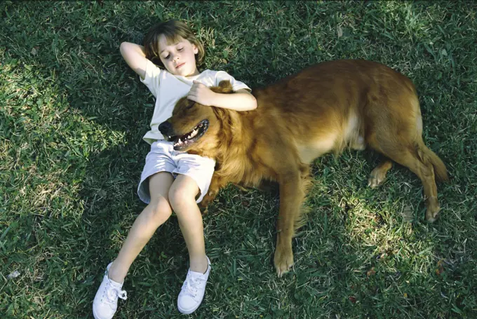 High angle view of a girl lying on the lawn with her dog