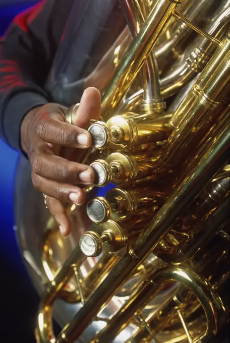 Close-up of a person's hands playing the tuba