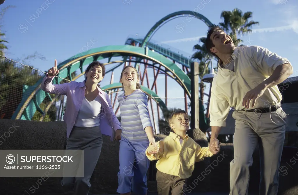 Parents walking with their son and daughter in an amusement park