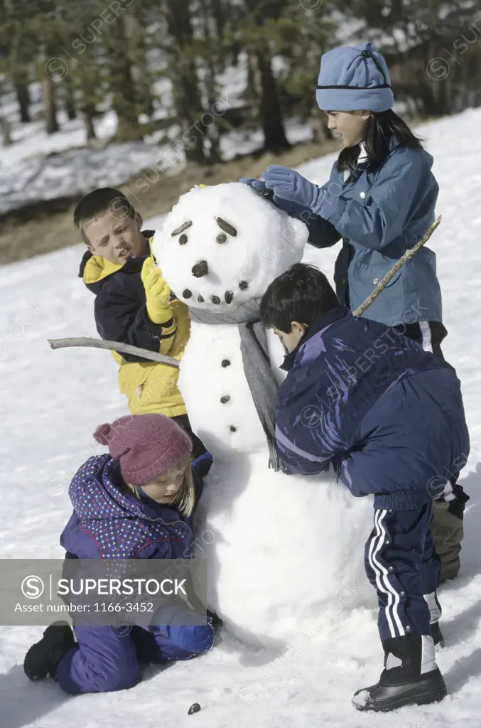 Two boys and two girls building a snowman