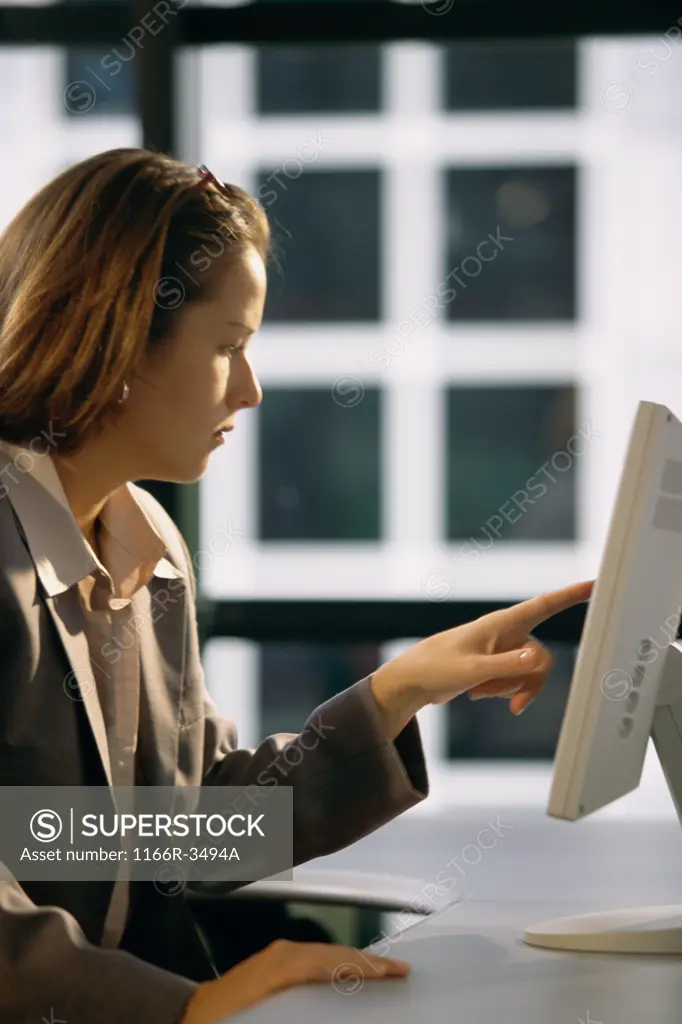 Side profile of a businesswoman touching the screen of a computer monitor