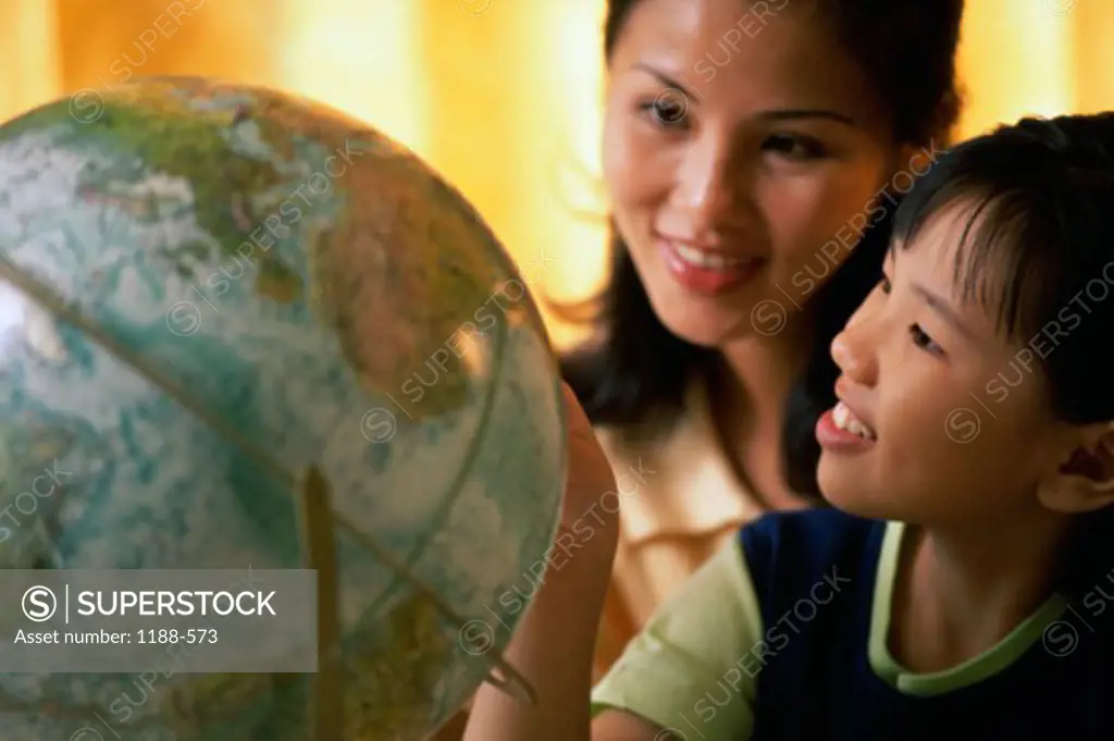 Close-up of a mother and daughter looking at a globe