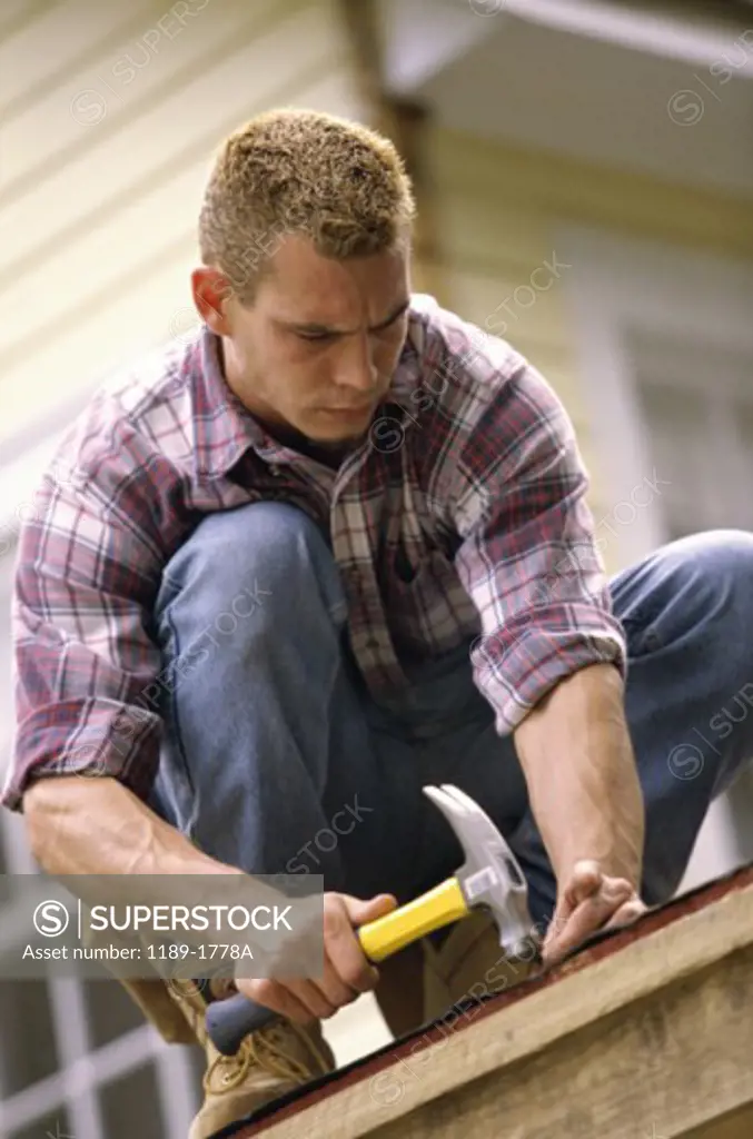 Young man hammering a nail into a wooden board