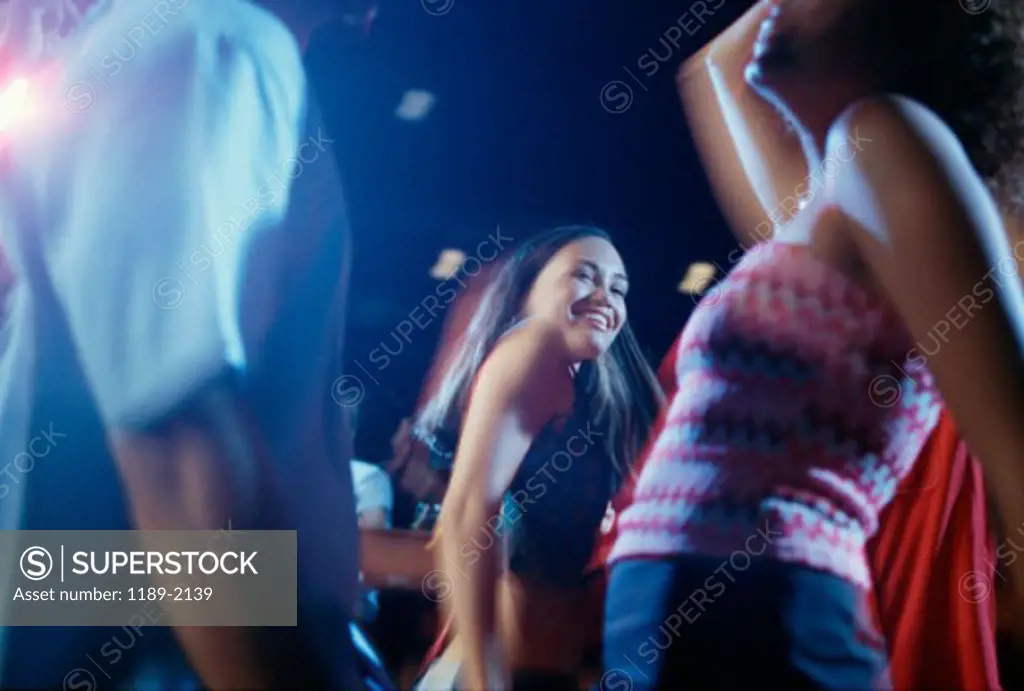 Two young women and a young man dancing at a nightclub