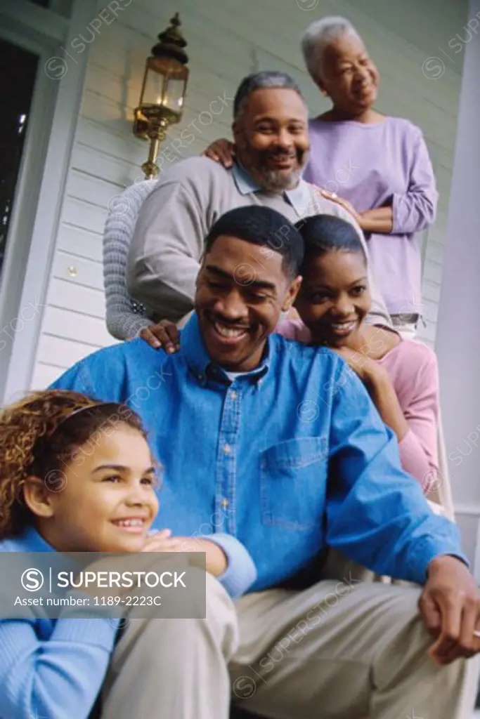 Grandparents sitting on the front porch with their son and granddaughter