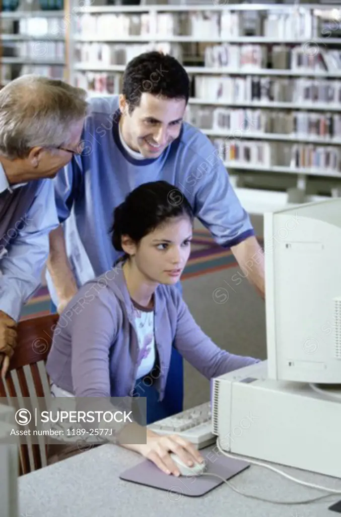 Male teacher with a teenage boy and a teenage girl in front of a computer