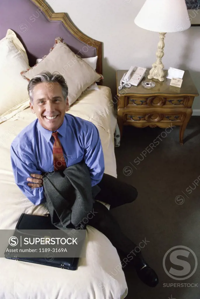 Portrait of a businessman sitting on a bed in a hotel room