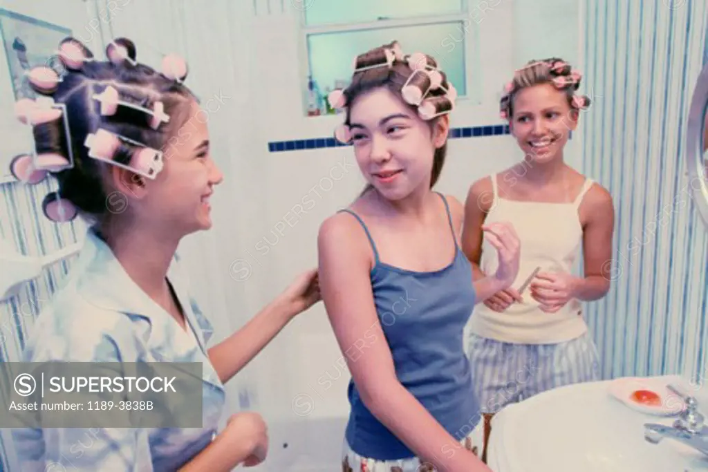 Three teenage girls wearing hair curlers