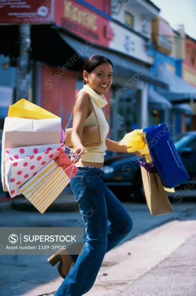 Portrait of a young woman walking with shopping bags