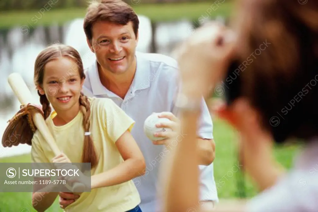 Father holding a baseball bat standing with his daughter