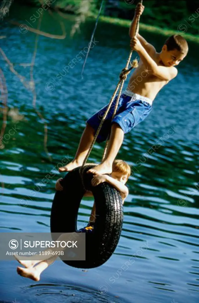 Two boys playing on a tire swing