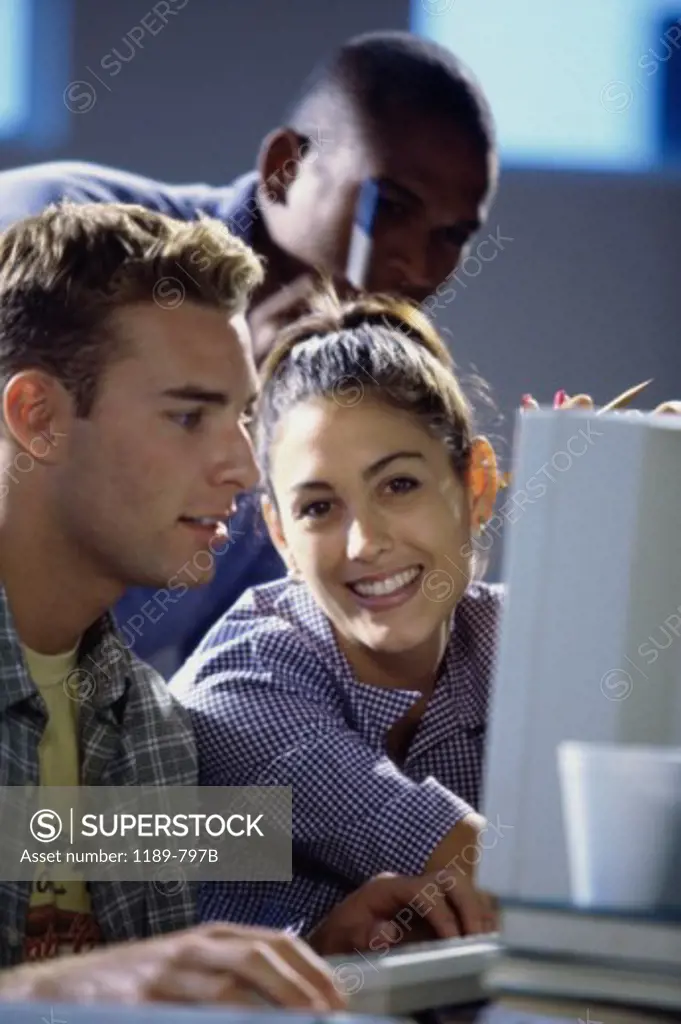 Side profile of two young men and a young woman in front of a computer