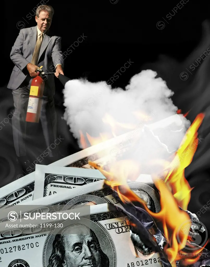 Businessman extinguishing fire on American dollar bills with a fire extinguisher