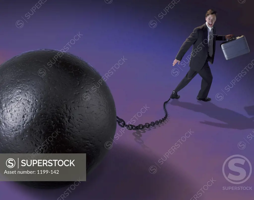 Businessman attached to a ball and chain