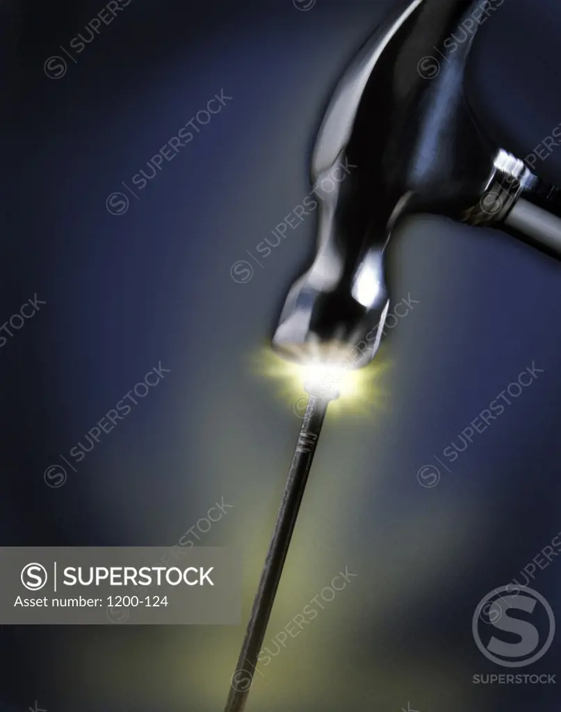 Close-up of a hammer striking a nail