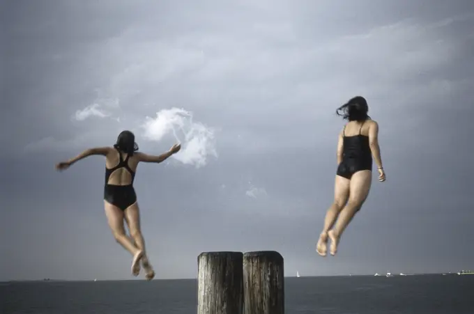 Girls jumping off dock into water