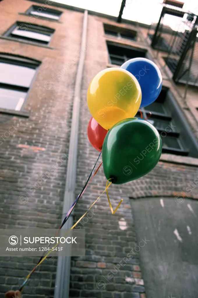 Colorful helium balloons in front of building,