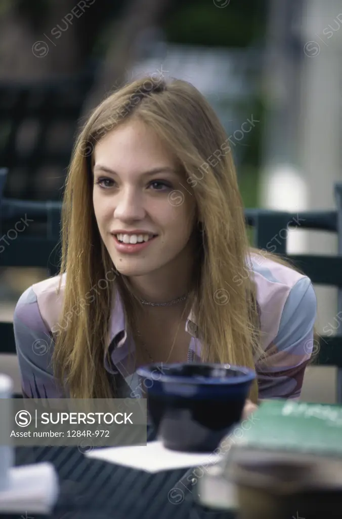 Teenage girl sitting at a table outdoors