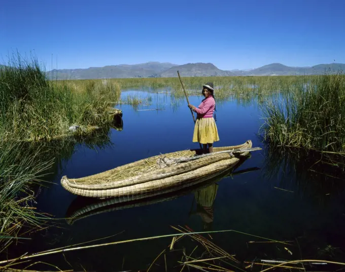 Uros Indian woman rowing a reed boat, Lake Titicaca, Peru