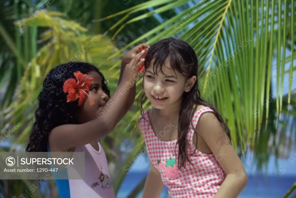 Close-up of a girl putting a flower in her friend's hair, Maldives