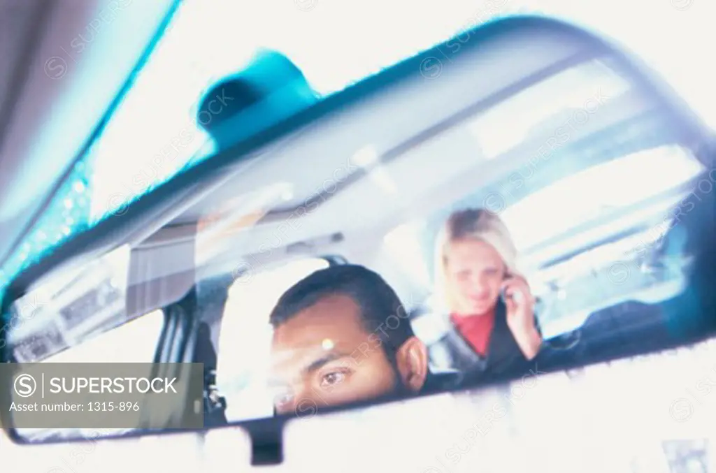 Reflection of a young man and young woman in a rearview mirror of a car