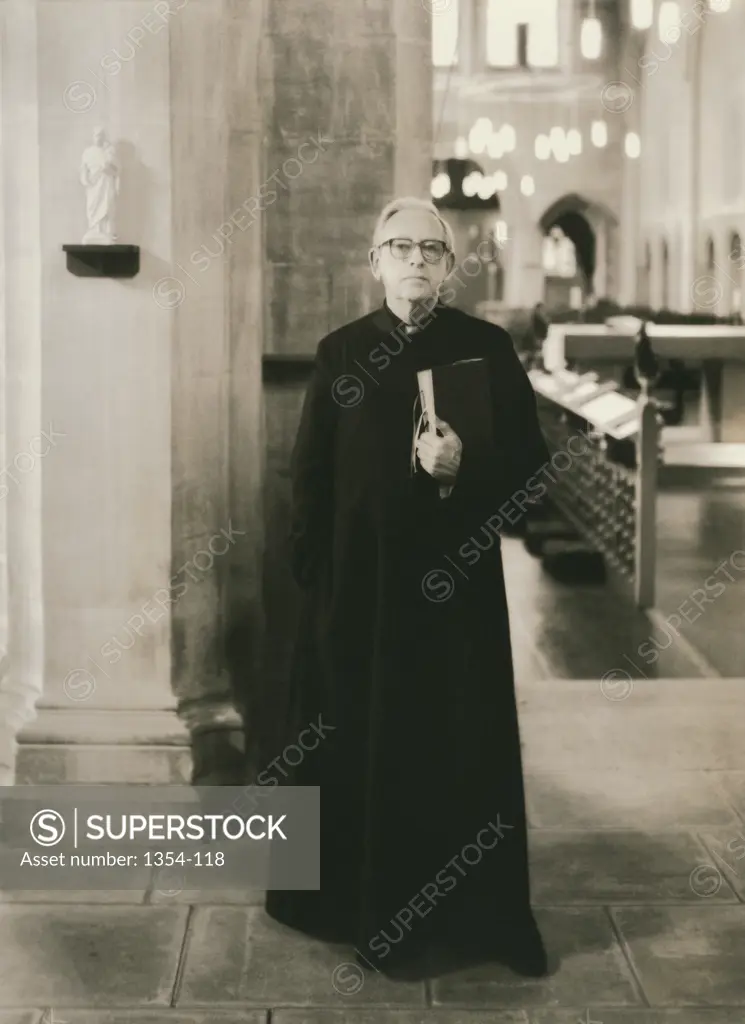 Monochrome portrait of a clergyman holding a book in an historic church setting. (Portrait of a priest standing in a church)