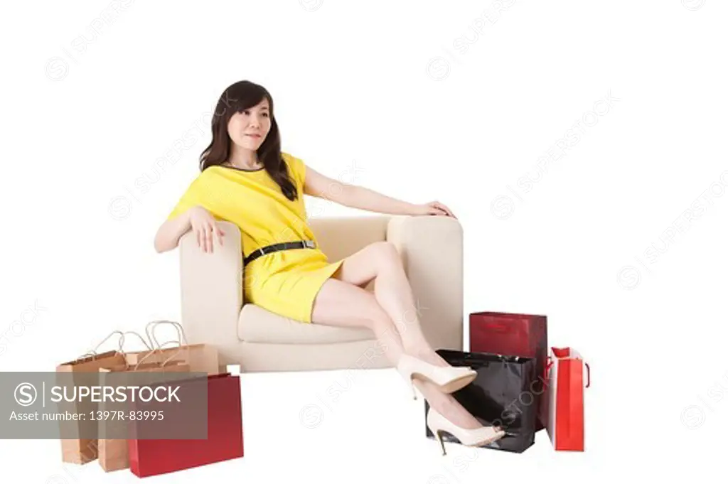 Mature woman sitting on sofa with shopping bags