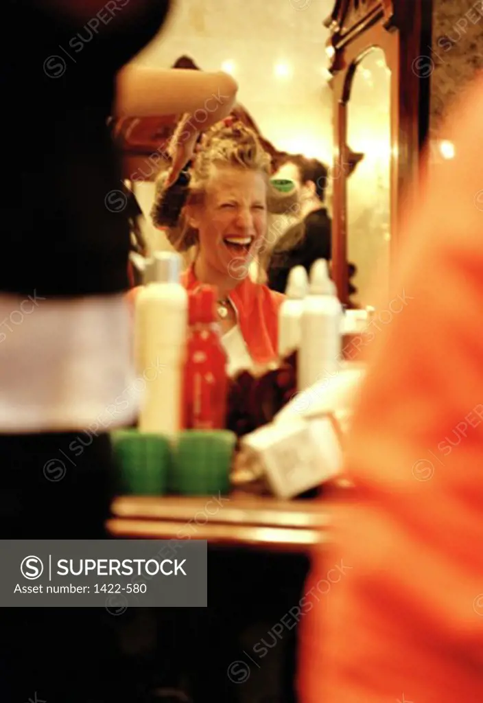 Hairdresser adjusting curlers in a young woman's hair