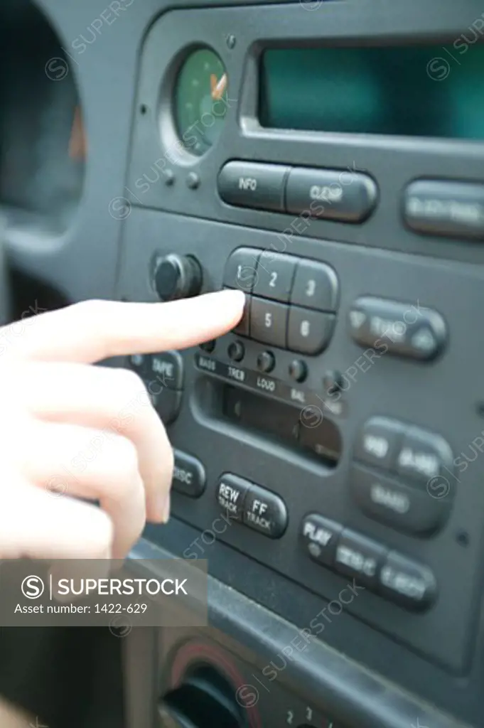 Close-up of a person's finger pressing the button of a car stereo