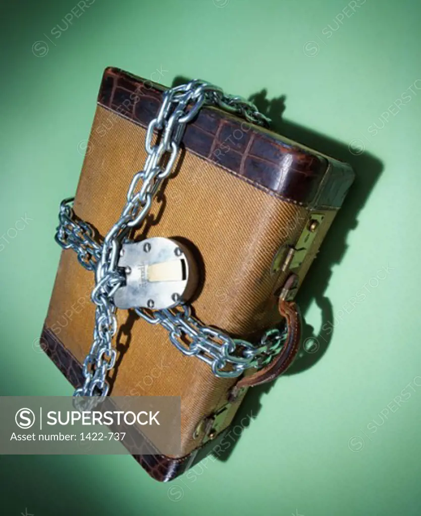Close-up of a suitcase locked with a chain