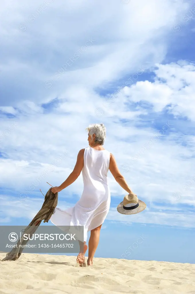 Mature woman in a white suit enjoying an afternoon on the Islantilla beach, Huelva