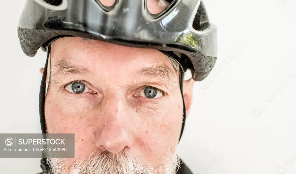 Close up of old man wearing a bicycle helmet. Portrait of elderly person living an active life with healthy lifestyle.