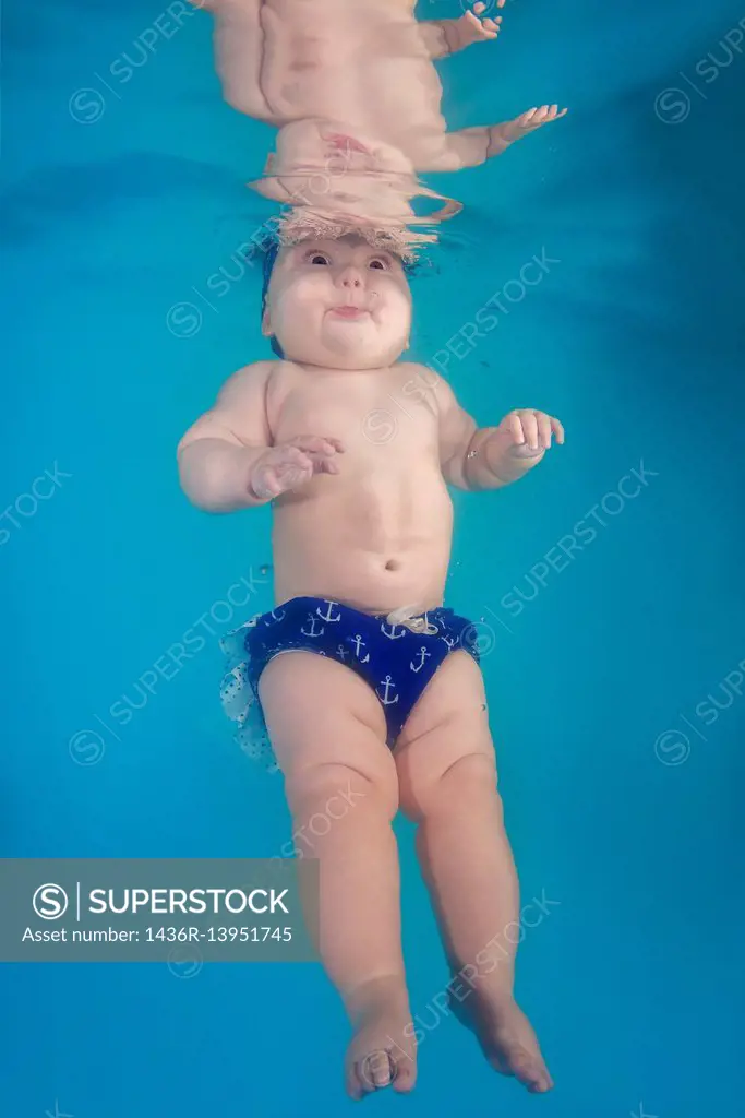 Little plump girl learns to swim underwater in the pool.