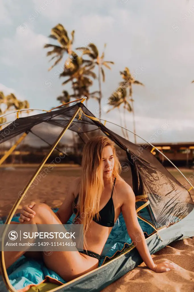 Woman in tent on sandy beach, Princeville, Hawaii, US