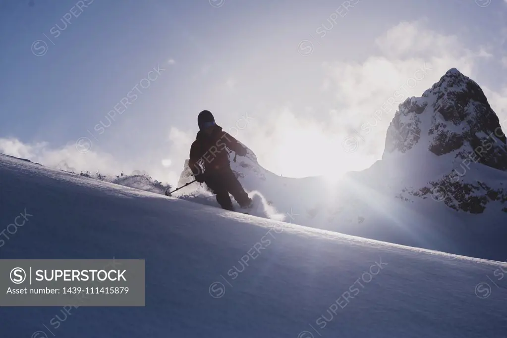 Silhouetted skier skiing downhill, low angle view, Squamish, British Columbia, Canada