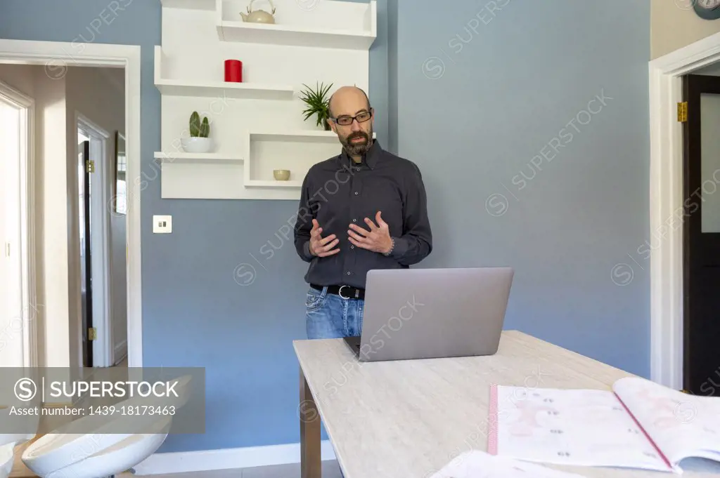 UK, Surrey, Man having virtual meeting via laptop at home