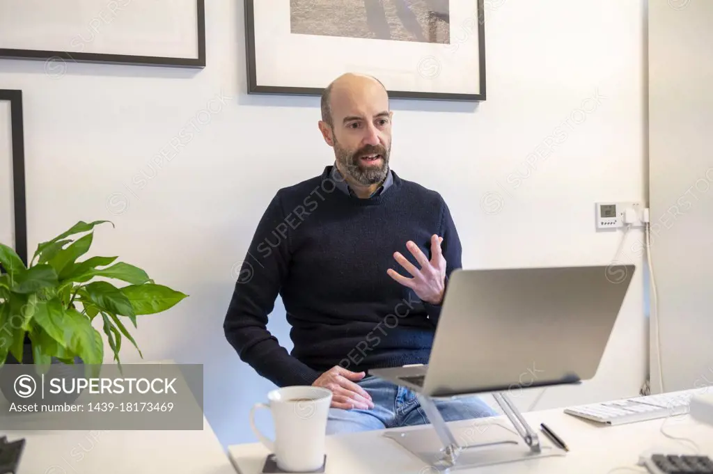 UK, Surrey, Man having virtual meeting via laptop at home