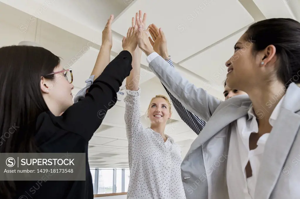 Germany, Bavaria, Munich, Business people doing high-five together in office