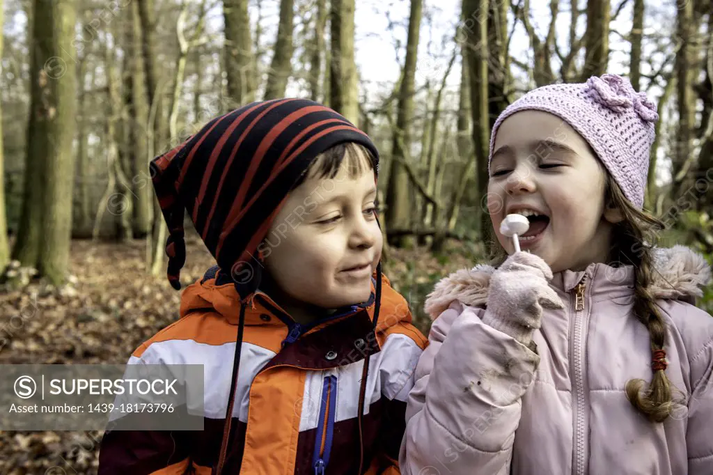 UK, Smiling boy looking at girl eating lollipop in Autumn park