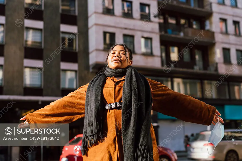 Young woman with arms outstretched in city