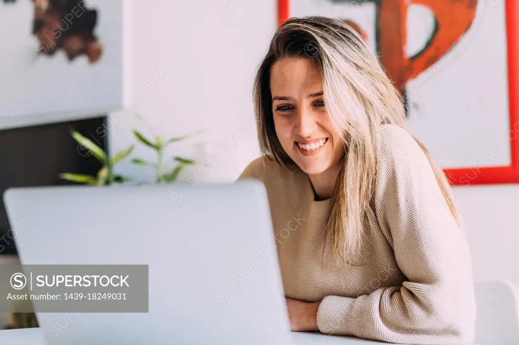 Italy, Young woman using laptop at home