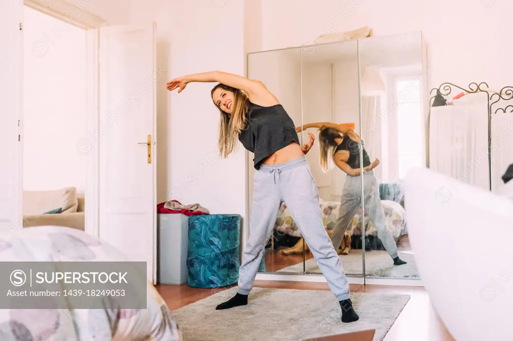 Italy, Young woman stretching at home