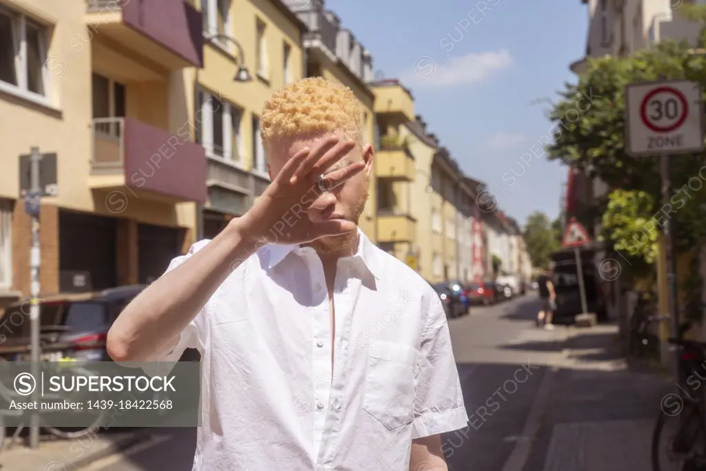 Germany, Cologne, Albino man in white shirt on street