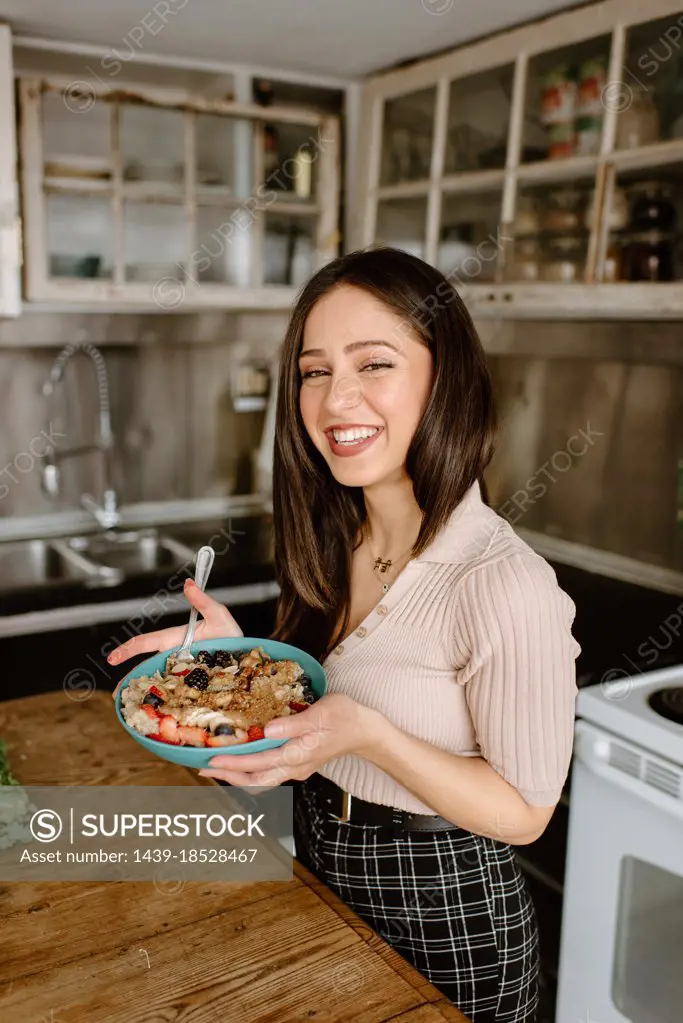 Smiling young woman holding granola bowl