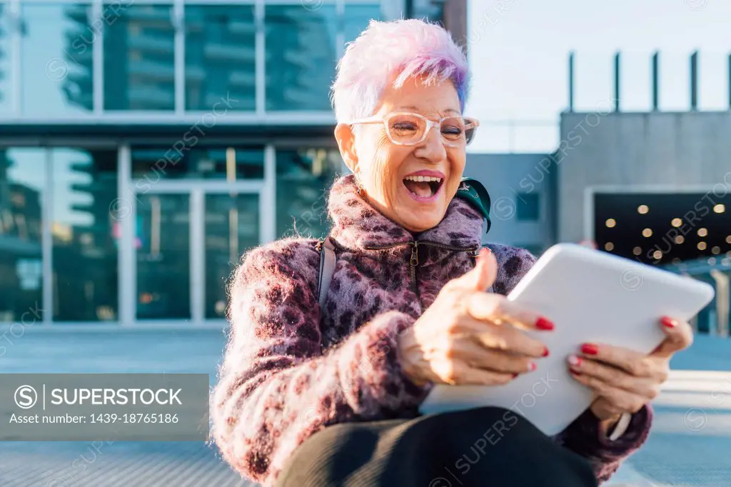 Italy, Fashionable senior woman using tablet in city