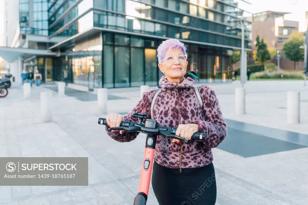 Italy, Fashionable senior woman with push scooter in city