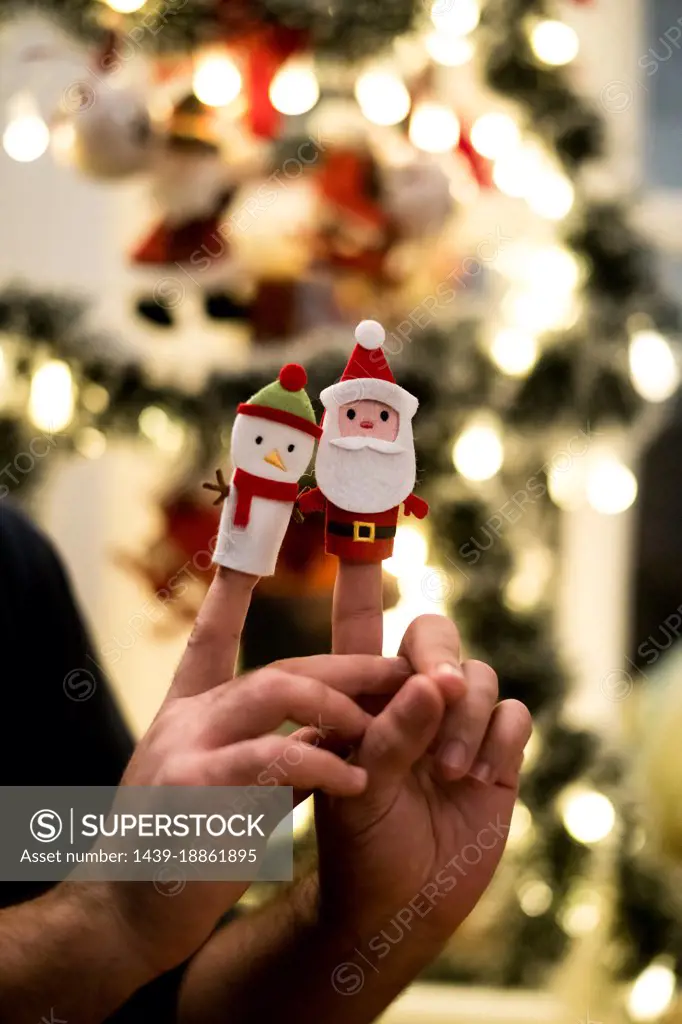 Close-up of hands with finger puppets of Santa and snowman