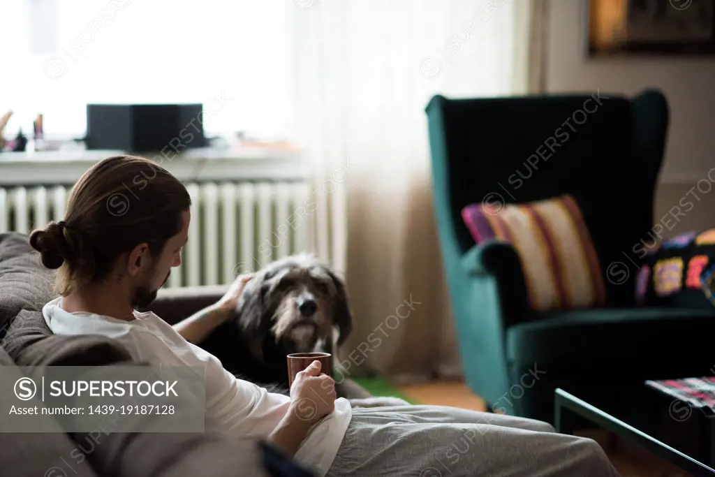 Man with dachshund relaxing on sofa